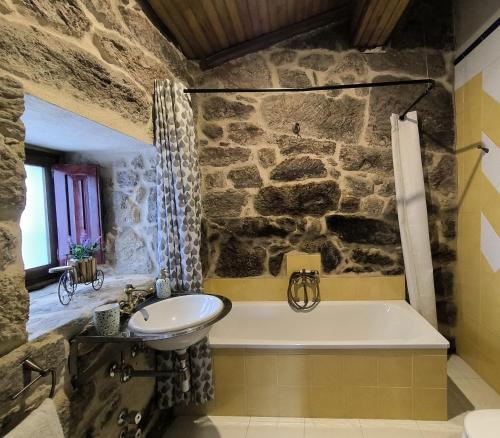 uma casa de banho em pedra com uma banheira e um lavatório em Casa Bodega Sacra em Pereiro de Aguiar