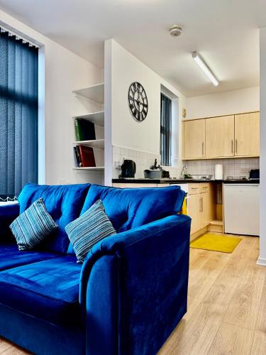 a blue couch in a living room with a kitchen at Rooms Near Me - Apartment 4, Smart Tv, Free Parking in Halesowen