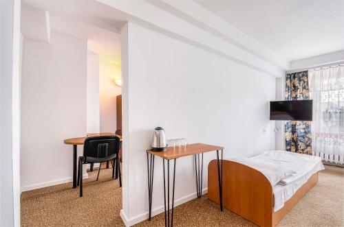 a bedroom with a bed and a table and a desk at Hotel Biała Gwiazda in Kraków