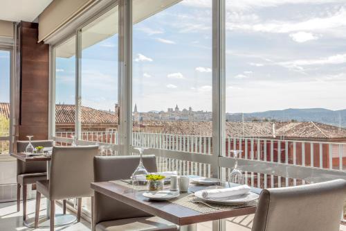 a dining room with a table and chairs and a large window at Eurostars Toledo in Toledo