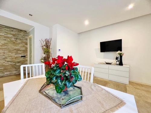 a vase with red flowers on a table in a room at Rosa di Mare in Capaci