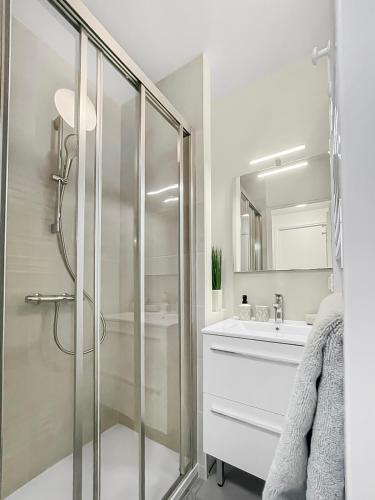 une salle de bain blanche avec une douche et un lavabo dans l'établissement L'Odyssée Nazairienne, à Saint-Nazaire