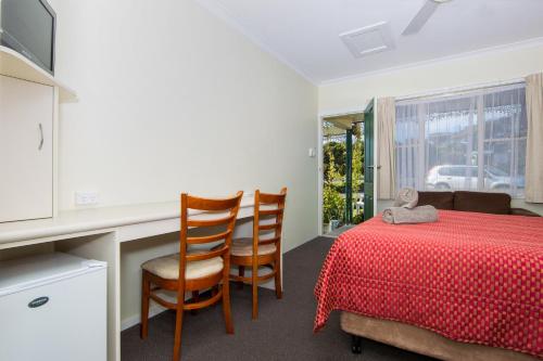 a bedroom with a table and two chairs and a red tablecloth at Wintersun Gardens Motel in Bicheno