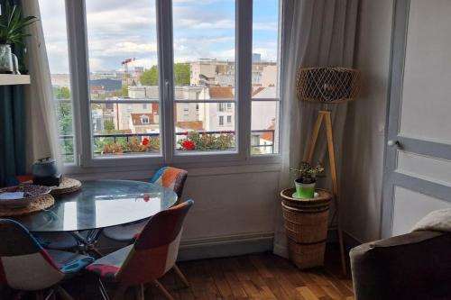 uma mesa e cadeiras num quarto com uma janela em Appartement cosy avec balcon et vue dégagée em Montreuil