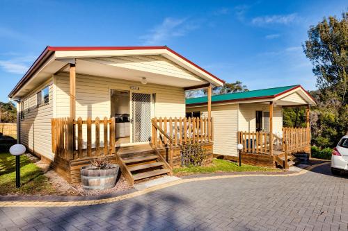 a tiny house with a porch and a driveway at Wintersun Gardens Motel in Bicheno