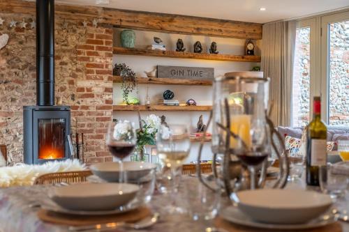 a table with glasses of wine and a fireplace at Horse Yard Barn in Warham