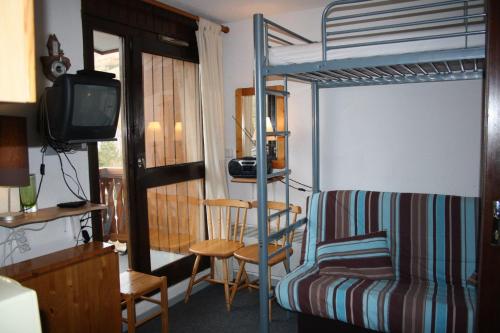- une chambre avec des lits superposés, une chaise et une télévision dans l'établissement Plein Sud - 1501 - Studio pied des pistes 2 pers, à Les Deux Alpes