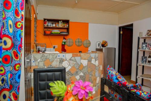 een woonkamer met een oranje muur en een stoel bij Cozzy one bedroom apartment in Ukunda