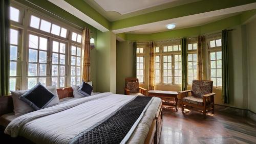 - une chambre avec un grand lit dans une pièce dotée de fenêtres dans l'établissement Ecotel kalimpong, à Kalimpong
