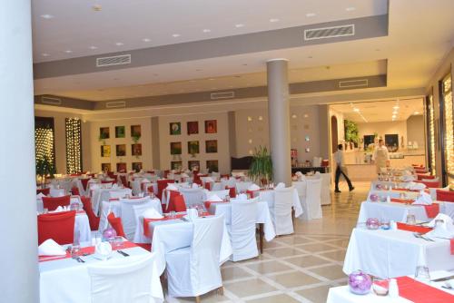 um salão de banquetes com mesas brancas e cadeiras vermelhas em Tamra Beach Resort em Sharm el Sheikh