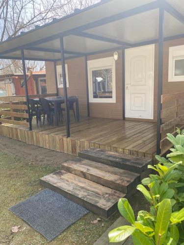 a house with a deck with a table and chairs at Càmping Molí de Vilamala in Les Planes d'Hostoles