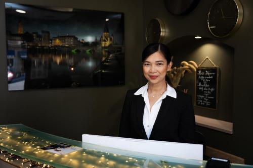 a woman sitting at a table with a laptop at Hôtel Escurial - Centre Gare in Metz