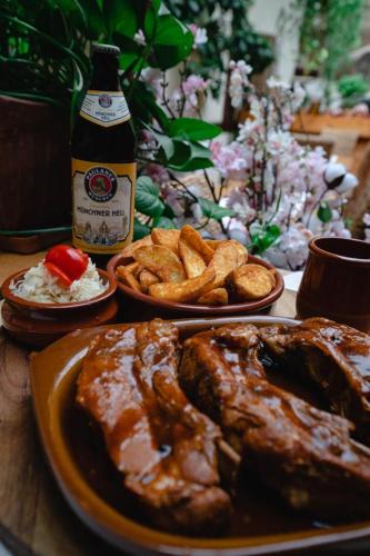 a table with plates of food and a bottle of beer at Pensiunea Gasthaus Alte Post in Sighişoara