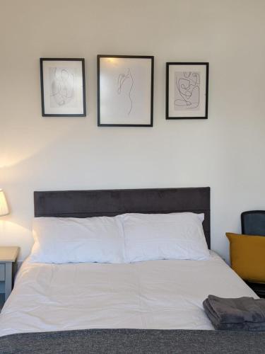 sypialnia z białym łóżkiem z 3 obrazami na ścianie w obiekcie *Feel at home* 3bed 2bath house Cleethorpes w mieście Grimsby