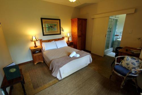 a bedroom with a large bed and a chair at Figtree Lane Lodge in Richards Bay