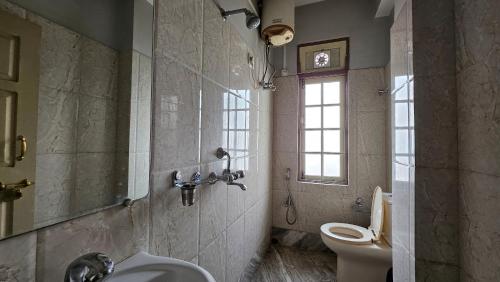 a bathroom with a sink and a toilet and a window at Ecotel kalimpong in Kalimpong