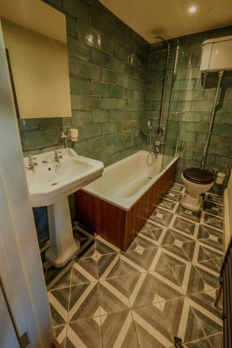 a bathroom with a sink and a tub and a toilet at The White Horse Hotel in Leiston