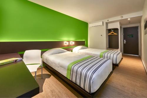 two beds in a room with a green wall at City Express Junior by Marriott Juarez Consulado in Ciudad Juárez