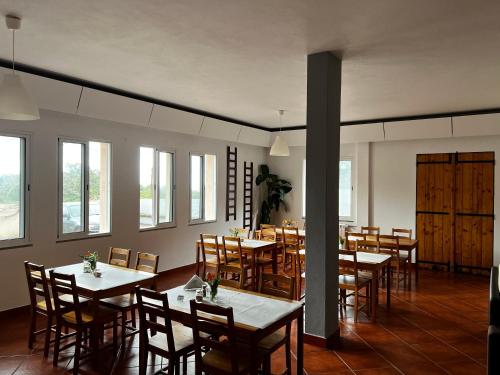 ein Esszimmer mit Tischen, Stühlen und Fenstern in der Unterkunft Casa Os Manos in Santana