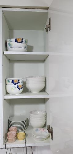 a white cabinet with plates and bowls on shelves at Comfy & Cozy in Seoul