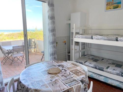 Cette chambre comprend une table et deux lits superposés. dans l'établissement Appartement avec terrasse et parking, accès direct plage - FR-1-782-5, au Barcarès