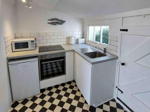 a kitchen with white appliances and a checkered floor at Amazing Sea View Chalet. 1 minute from the sea , harbour and Cobb and very nr to fabulous pubs , restaurants and activities. Sleeps 4 with parking in Lyme Regis