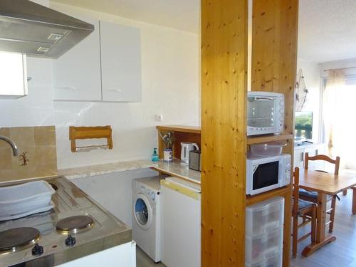 une cuisine avec des armoires blanches, une table et un micro-ondes dans l'établissement Appartement avec terrasse près de la plage - FR-1-782-12, au Barcarès