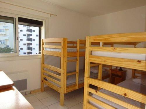 une chambre avec deux lits superposés et une fenêtre dans l'établissement Appartement spacieux 3P avec clim, parking et accès plage direct - FR-1-782-16, au Barcarès