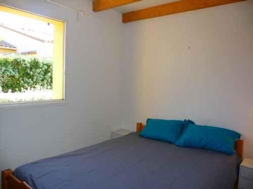 une chambre avec un lit avec des oreillers bleus et une fenêtre dans l'établissement Villa 4 pers, 300m plage, parking, terrasse, BBQ - FR-1-782-25, au Barcarès