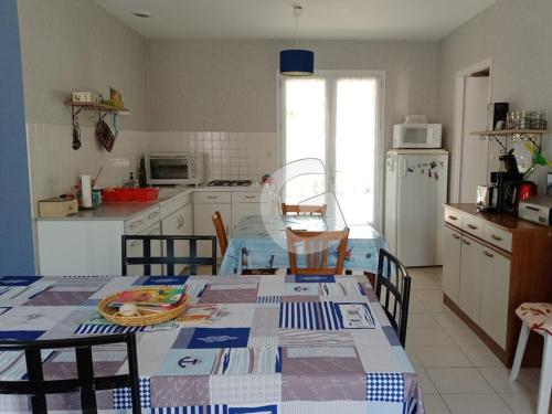 une cuisine avec une table, des chaises et un réfrigérateur dans l'établissement Maison à 150m de la plage du Rocher, 4 pers, terrasse, garage, parking privé, à Longeville sur Mer - FR-1-357-321, à Longeville-sur-Mer