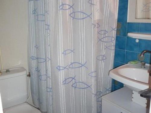 La salle de bains est pourvue d'un rideau de douche avec du poisson bleu. dans l'établissement Studio à 50m de la plage, parking privé - FR-1-782-23, au Barcarès