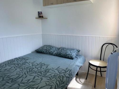 un lit dans une chambre avec une chaise et un oreiller dans l'établissement Appartement rénové 2P à 100m de la plage avec parking privé - FR-1-782-30, au Barcarès
