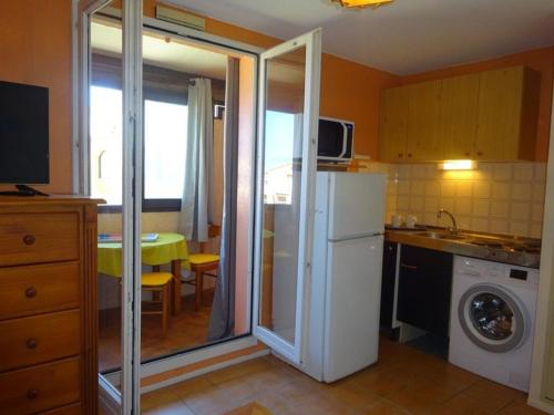 une cuisine avec un réfrigérateur blanc et une table dans l'établissement Studio cabine à 50m de la plage, Le Barcarès - FR-1-782-32, au Barcarès