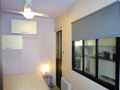- une chambre avec un ventilateur de plafond et une grande fenêtre dans l'établissement Appartement T2 cabine climatisé, proche plage, parking privé, équipé pour 6 personnes - FR-1-782-33, au Barcarès