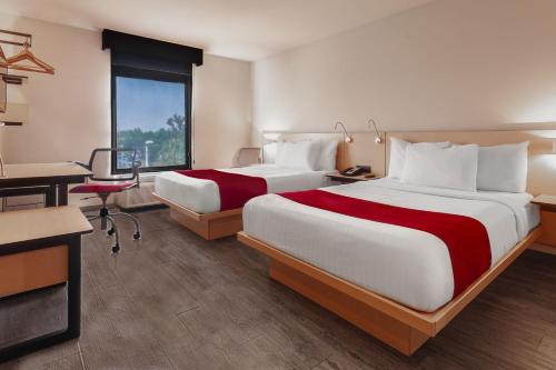 a hotel room with two beds and a desk at City Express by Marriott Leon in León