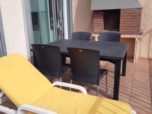 une table noire et des chaises sur une terrasse dans l'établissement Duplex avec parking privé, ascenseur, accès plage et WiFi - 2 chambres - FR-1-782-44, au Barcarès
