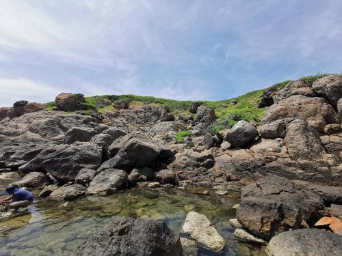 a man standing in the water on a rocky hill at NEW WAVE HOMESTAY in Ấp Khánh Phước (1)