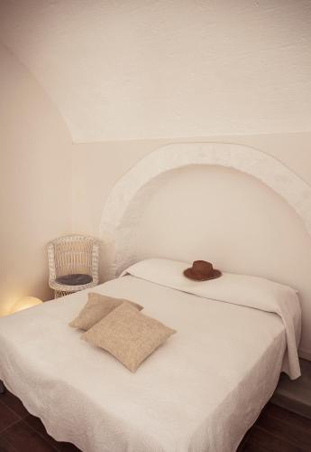 un letto bianco con un cappello sopra di Casa Vita Lenta by Momò Apulia a Monopoli