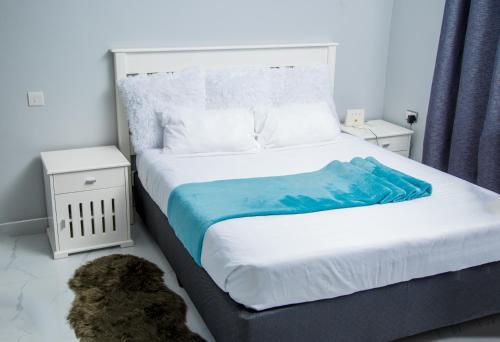 una camera da letto con un grande letto con una coperta blu sopra di Modern Village Apartments a Chipata