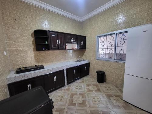 una cucina con armadi neri e frigorifero bianco di RESIDENCE LA VARENNE, DSCHANG a Dschang