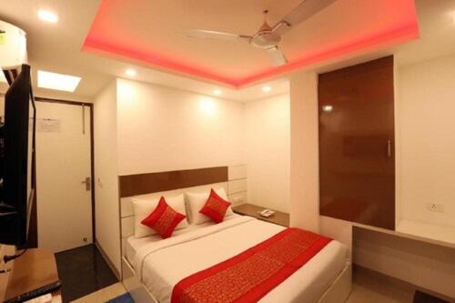 a bedroom with a bed with red pillows and a ceiling at Del Fox Holidays New Delhi Connaught Palace 4 Minuit and 7 Minuit VFS Sivaji Stadium Metro Station in New Delhi