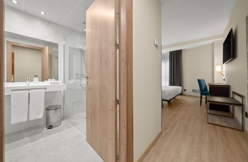 Zimmer mit einem Bad mit Waschbecken und einem Schreibtisch in der Unterkunft Hotel Zentral Gijón Rey Pelayo in Gijón