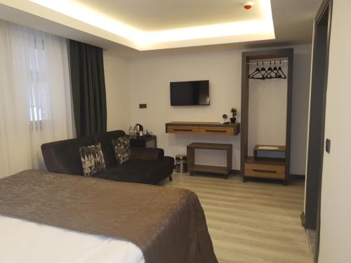 a hotel room with a bed and a couch and a television at Hotel Kriti in Antalya