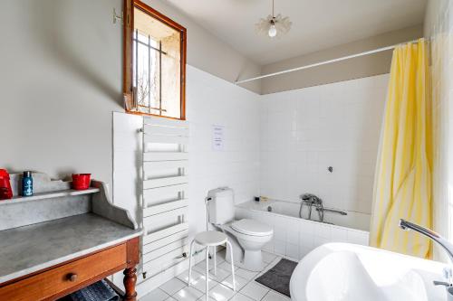 a bathroom with a toilet and a tub and a sink at Sorbède - Charmante maison pour 10 personnes in Montussan