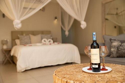 a bottle of wine on a table next to a bed at The Four Palms in Kilifi