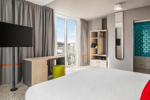 a bedroom with a bed and a desk and a tv at Quadro Hotel, Trademark Collection by Wyndham in St Julian's