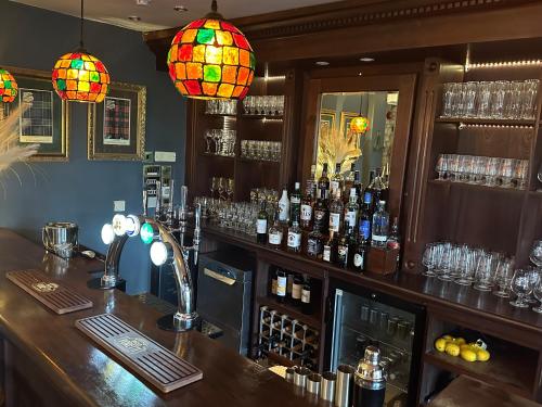 a bar with bottles of alcohol and lights at Burford Lodge Hotel - Adults only in Burford