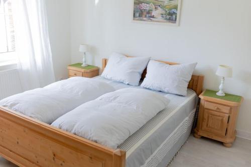 a wooden bed with white pillows and two night stands at Bungalow mit Basketballplatz in Lemgo