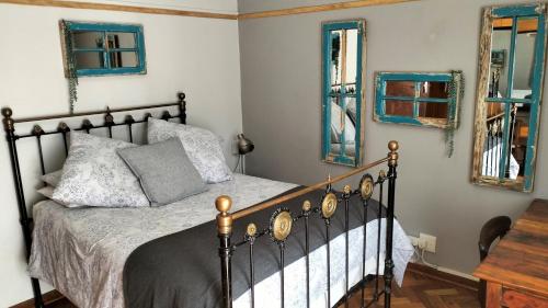 a bedroom with a bed and two mirrors at Anri Guesthouse in Bloemfontein