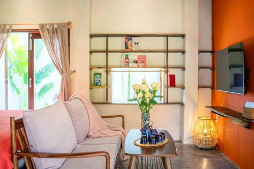 a living room with a couch and a vase of flowers on a table at Garden of Love Villa in An Bang, Hoi An in An Bang
